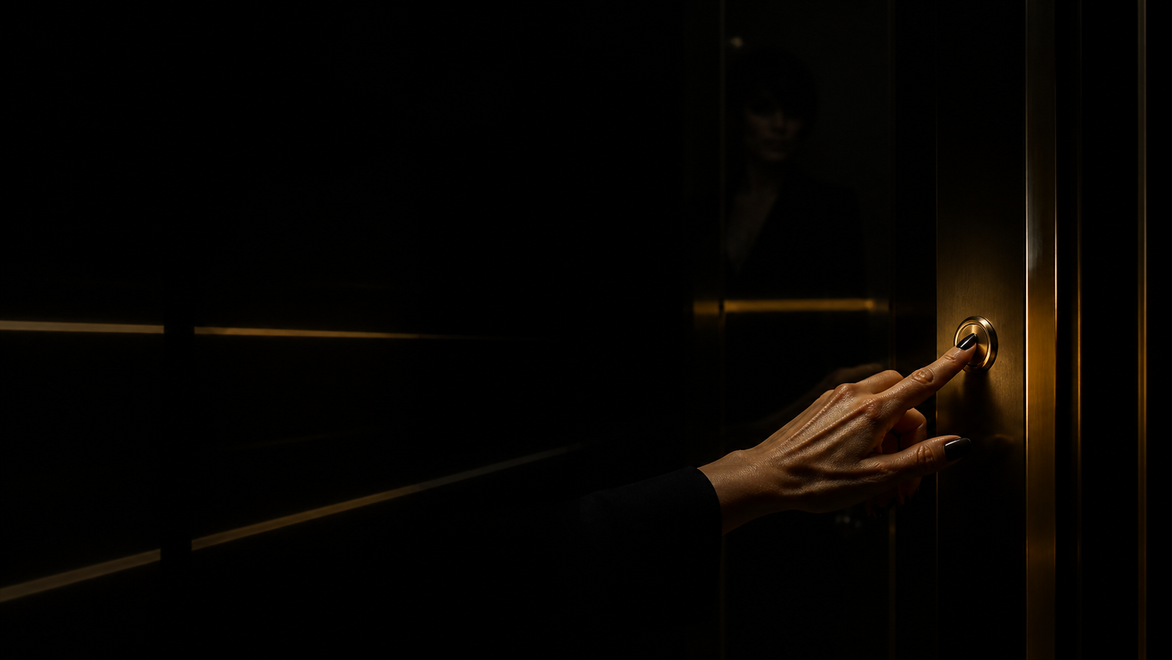 A hand pressing an elevator button in darkness